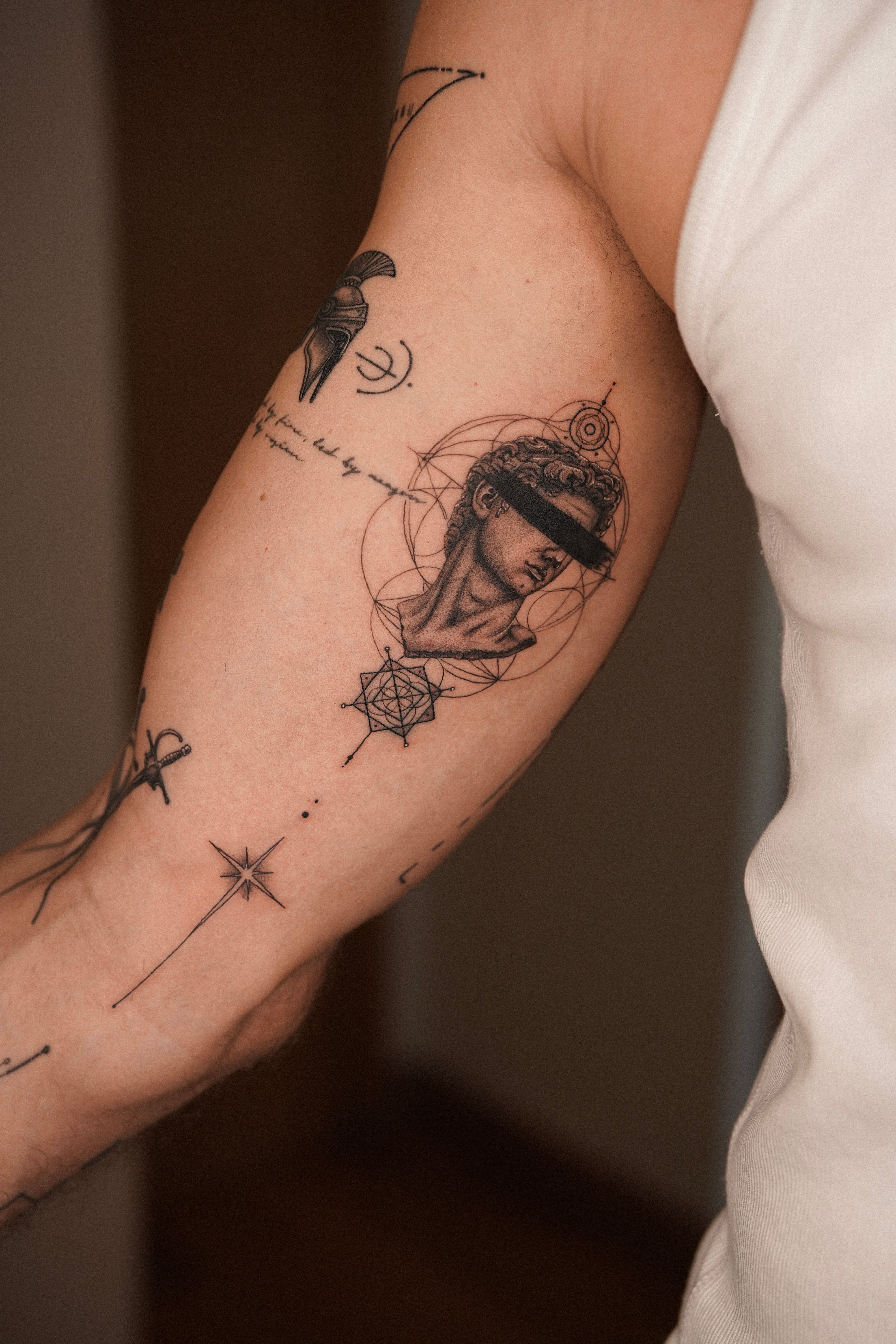 Blindfolded David fineline tattoo combining figurative micro-realism and geometric elements