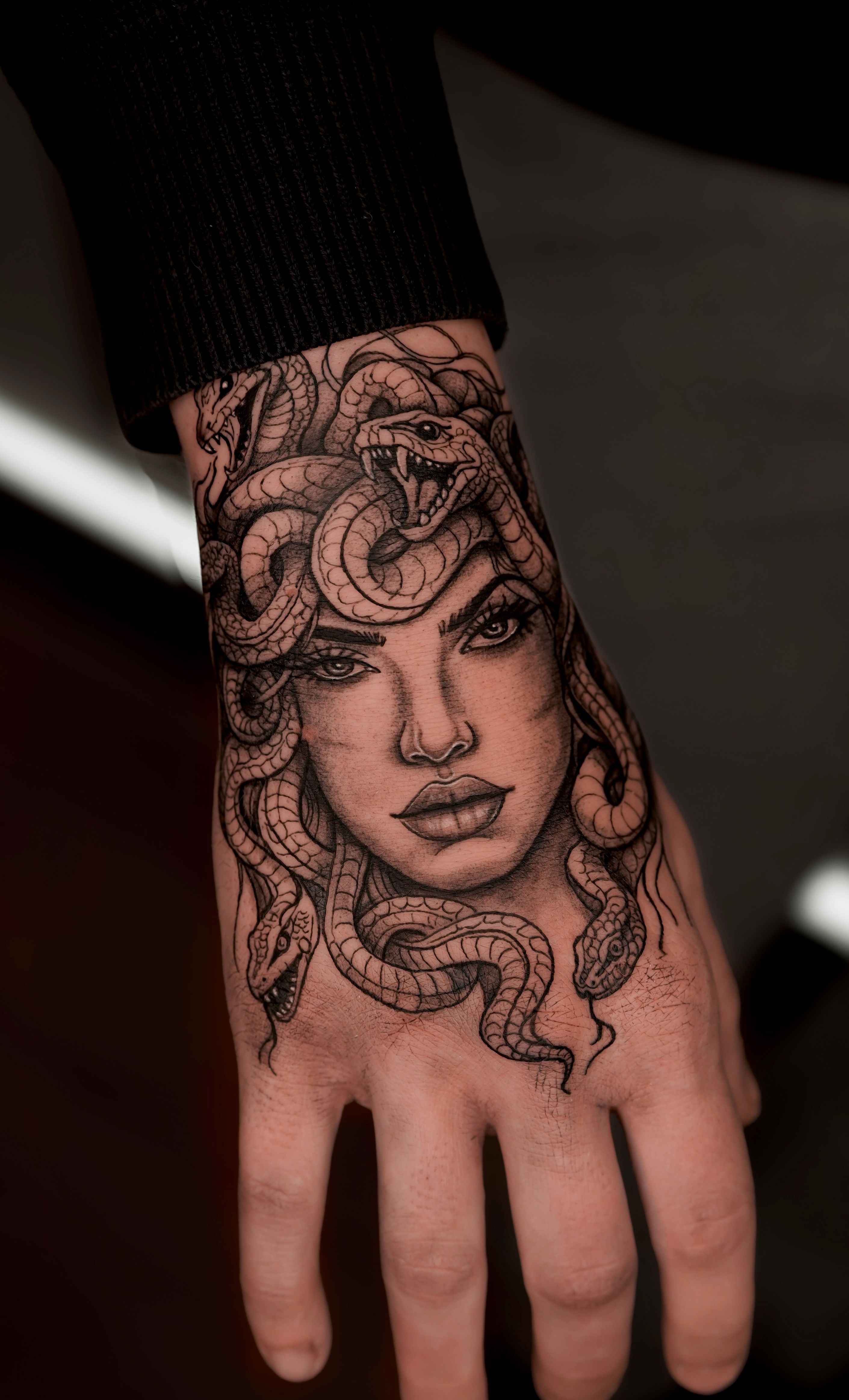 Black and grey Medusa realism tattoo on the hand