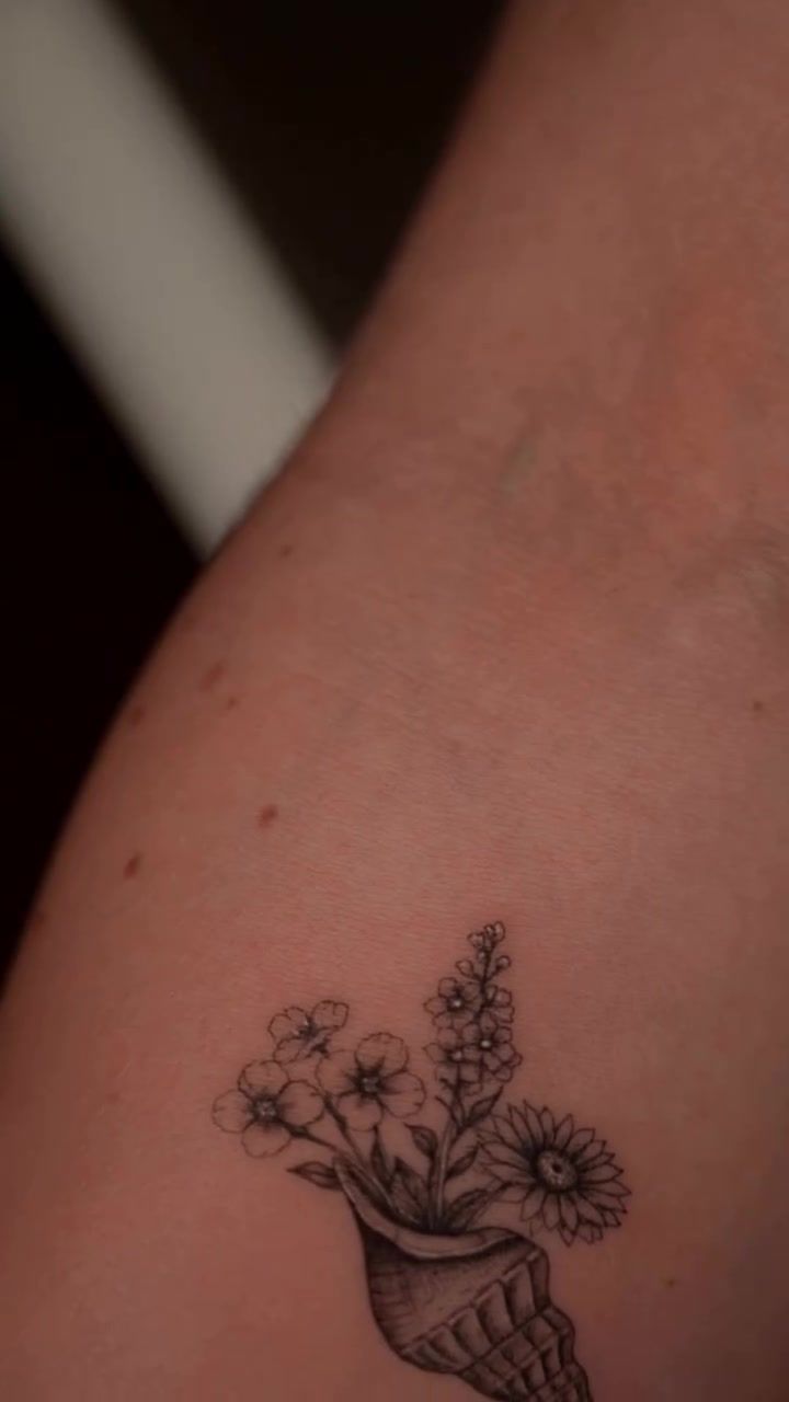 Conch shell with delicate floral fineline tattoo