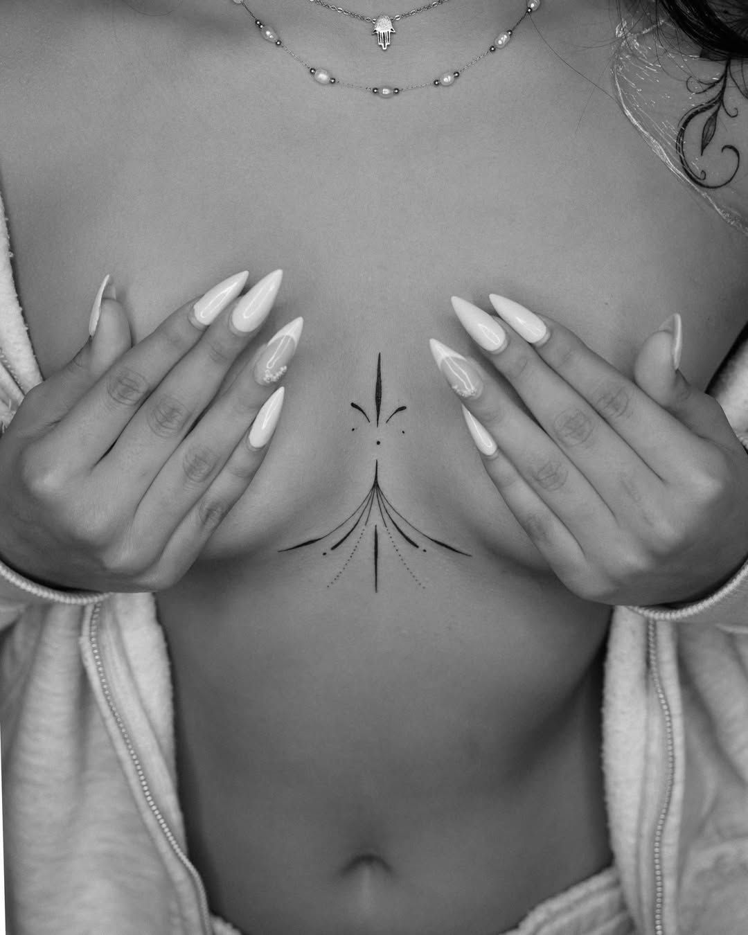 Ornamental sternum fineline tattoo showing precise geometric patterning and negative space
